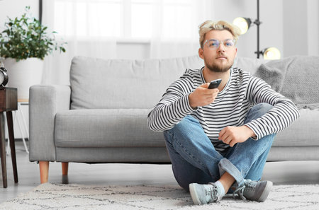 Young man wearing eyeglasses while watching TV at home