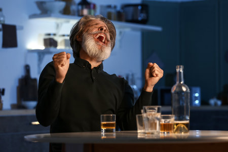 Angry senior man in kitchen at nightの写真素材