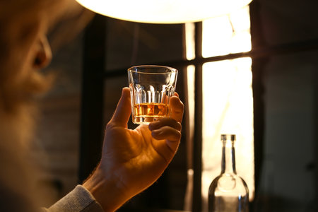 Senior man with glass of drink late in the evening at home, closeupの写真素材