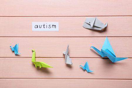 Word AUTISM and origami on color wooden backgroundの写真素材