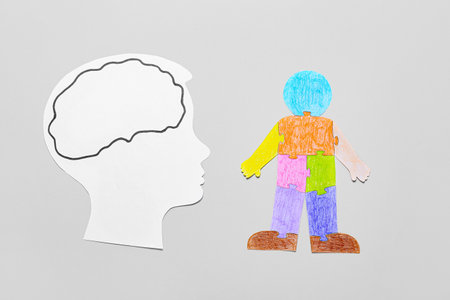 Paper head and colorful human figure on light background. Concept of autistic disorder
