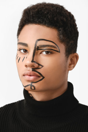 Young African-American guy with paint on face against light backgroundの写真素材