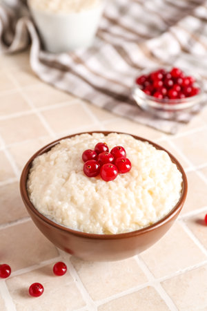 Bowl with delicious rice pudding and cranberry on tile tableの写真素材