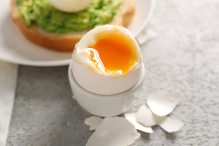 Holder with soft boiled egg and shell on gray table