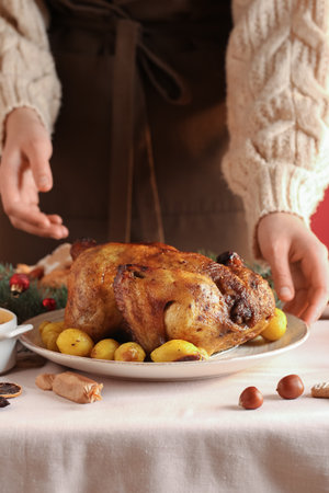 Woman with plate of Christmas chicken and potato on dining table, closeupの写真素材