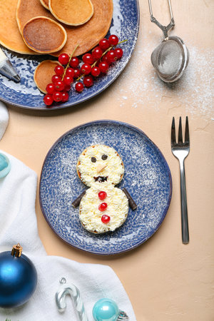 Plate with snowman made of pancakes, whipped cream and Christmas decor on beige tableの写真素材