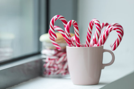 Cup with tasty candy canes on windowsillの写真素材
