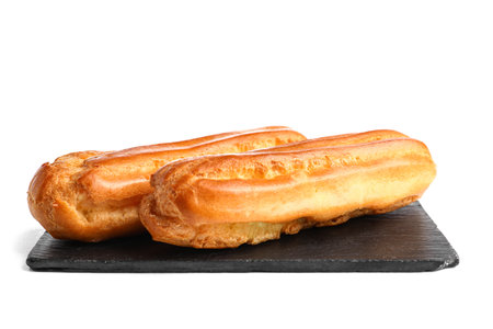 Slate board with tasty eclairs on white background