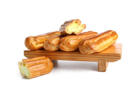 Wooden board with delicious eclairs isolated on white background