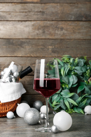 Glass of wine with white Christmas balls on wooden table, closeupの写真素材