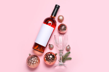 Bottle of wine with glass, Christmas balls and fir branches on pink backgroundの写真素材