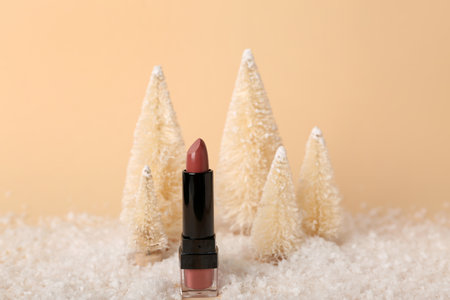 Composition with lipstick, decorative Christmas trees and snow on color backgroundの写真素材