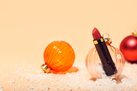 Composition with lipstick, broken Christmas ball and snow on color backgroundの写真素材