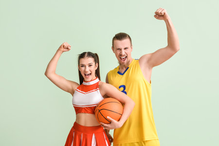 Cheerleader and basketball player on color background