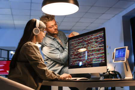 Young programmers working with computer in office at night