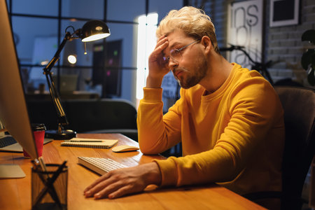 Male programmer working with computer late in the eveningの写真素材