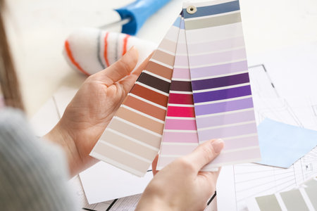 Woman with paint color palettes on light background