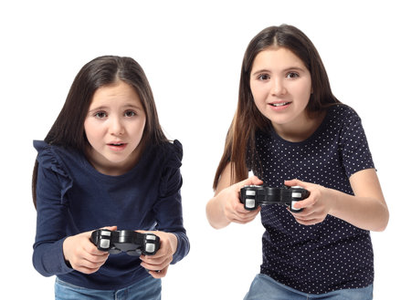 Cute twin girls playing video game on white backgroundの写真素材