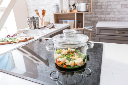 Cooking pot with healthy vegetables on electric stove in kitchenの写真素材