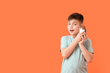 Cute little boy with chocolate Easter egg on color background
