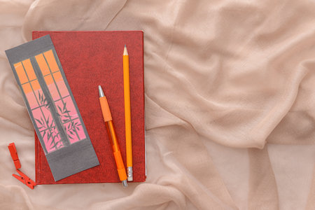 Book with bookmark, pencil and pen on color background