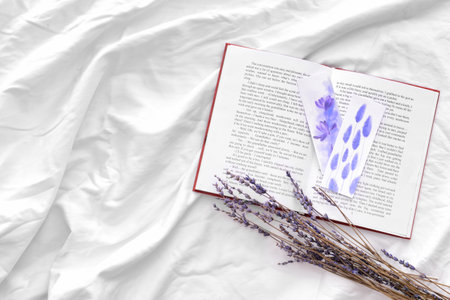 Book with bookmarks and lavender on bed