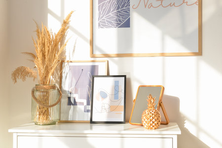 Shelf with vase, pictures and mirror near light wall