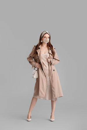 Fashionable young woman wearing mask on gray backgroundの写真素材