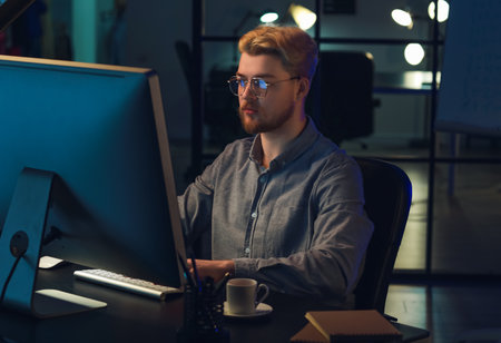 Handsome man using computer in office at night