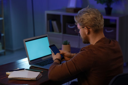 Handsome man using mobile phone at home late in the evening