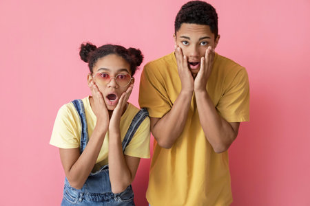 Surprised African-American brother and sister on color background