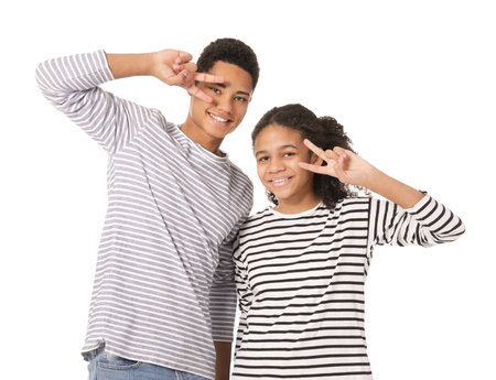African-American brother and sister showing victory gesture on white backgroundの写真素材