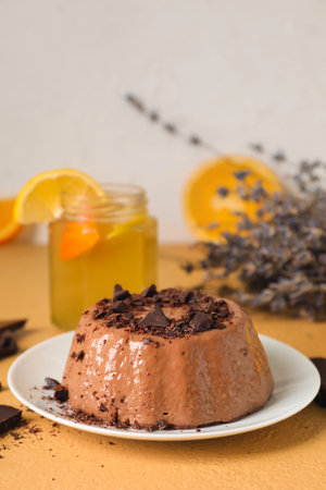 Plate with delicious pudding, chocolate and lemonade on beige table near gray wallの写真素材