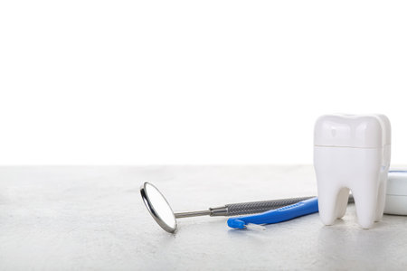 Plastic tooth with dental floss and tools on table against white backgroundの写真素材