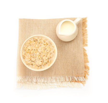 Bowl of tasty oatmeal, pitcher with milk and napkin isolated on white backgroundの写真素材