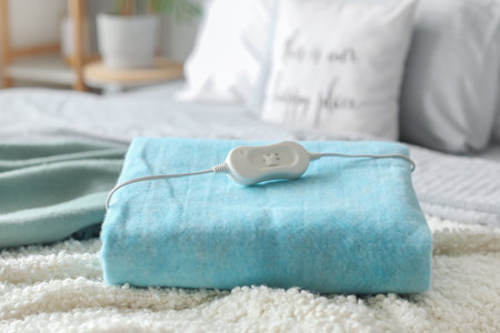 Folded electric heating pad with controller on bed in bedroom, closeupの写真素材