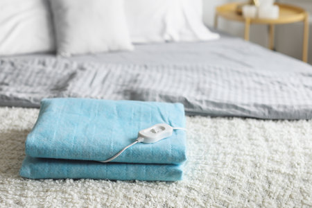 Folded electric heating pad with controller on bed in bedroom, closeupの写真素材