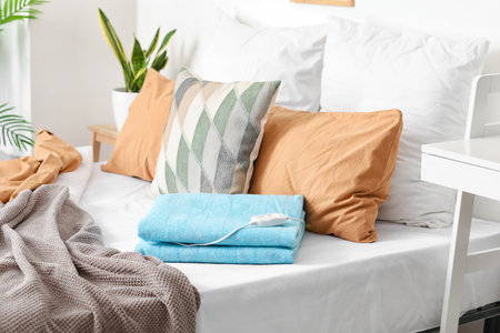 Bed with folded electric heating pad in the bedroomの写真素材