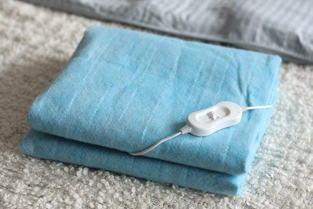 Folded electric heating pad with controller on white blanket in bedroom, closeupの写真素材