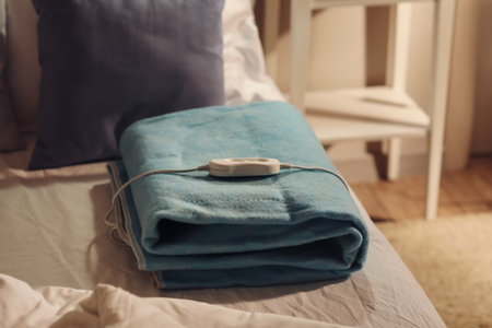 Folded electric heating pad with controller on bed at night, closeupの写真素材