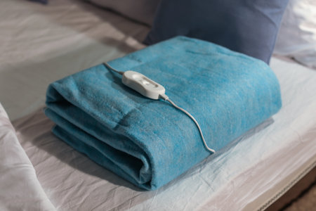 Folded electric heating pad with controller on bed at night, closeupの写真素材