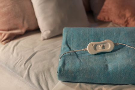 Folded electric heating pad with controller on bed at night, closeupの写真素材