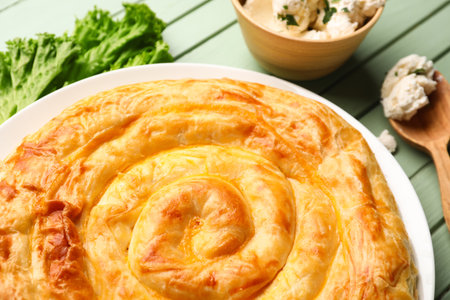 Plate with delicious cheese pie on green wooden tableの写真素材