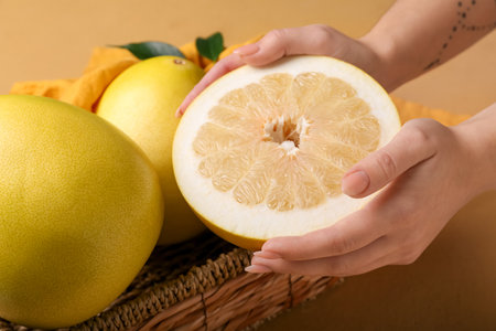 Female hands with sweet pomelo fruits on beige background, closeupの写真素材