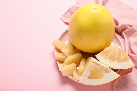 Plate with pomelo fruit and slices on pink background, closeupの写真素材