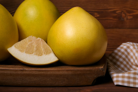 Wooden board with tasty pomelo fruit on table, closeupの写真素材
