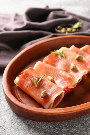 Plate with rolled slices of tasty ham on grunge background, closeupの写真素材