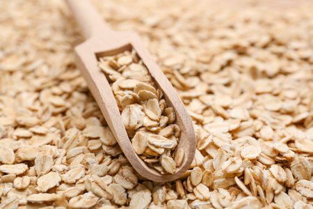 Heap of raw oatmeal with wooden scoop, closeupの写真素材