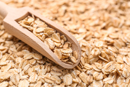 Heap of raw oatmeal with wooden scoop, closeupの写真素材
