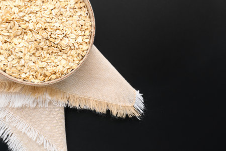Bowl of raw oatmeal on dark background